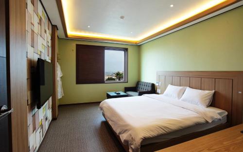 a bedroom with a large bed and a window at Hotel W Topdong in Jeju