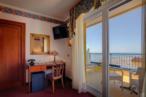 a room with a desk and a view of the ocean at Hotel Napoleon in Lido di Jesolo