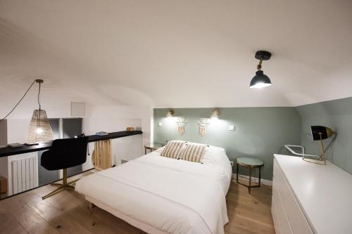 Schlafzimmer mit einem weißen Bett und einem Schreibtisch in der Unterkunft Le duplex d'André - Un écrin cosy et design pour 2 in Lyon