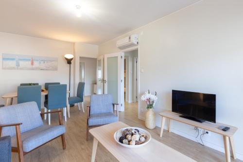 a living room with a television and blue chairs at Host Wise - Trendy Bright Flats with Jacuzzi - 5 min Beach in Matosinhos