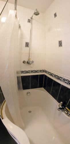 a bathroom with a bath tub with a shower at Station House, Dartmoor and Coast located, Village centre Hotel in South Brent