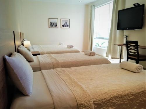 two beds in a room with a flat screen tv at Villa Oasis in Ica