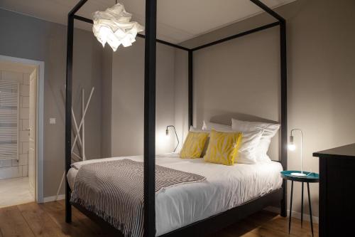 a bedroom with a black canopy bed with yellow pillows at The Suite Hotel Fabric in Frankfurt