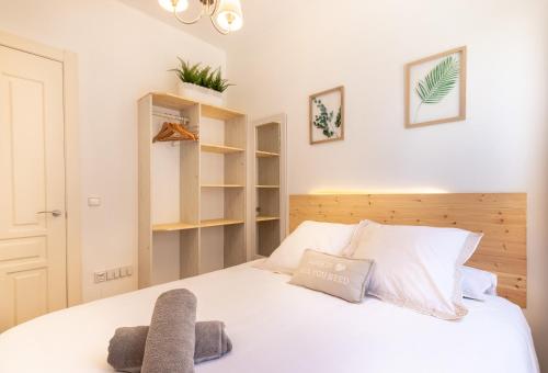 - une chambre avec un lit blanc et une tête de lit en bois dans l'établissement Apartment between Old Town & Guggenheim!! Private Parking, à Bilbao