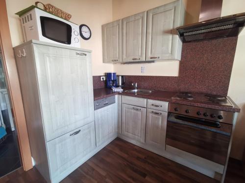 a kitchen with white cabinets and a sink and a microwave at Ferienlandhaus Höfer in Fulpmes