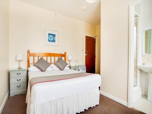 1 dormitorio con 1 cama blanca grande y lavamanos en OYO Godolphin Arms Hotel, en Newquay