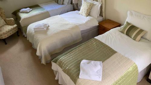a hotel room with three beds and a chair at Mill House - Devon Holiday Accommodation in Sidmouth