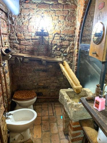 a brick bathroom with a toilet and a sink at Al Silter in Capriate San Gervasio