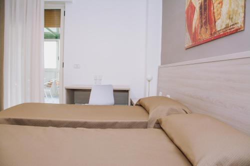 two beds in a room with a table and a painting at Hotel Piccolo Sogno in Pompei