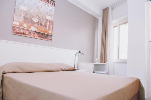 biała sypialnia z łóżkiem i oknem w obiekcie Hotel Piccolo Sogno w mieście Pompeje
