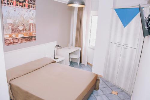 ポンペイにあるホテル ピッコロ ソーニョのベッドとデスクが備わる小さな客室です。