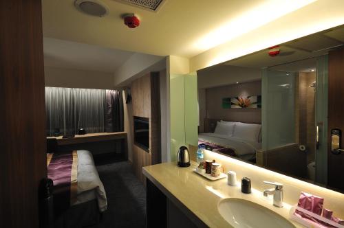 a bathroom with a sink and a bed and a mirror at Hoya Resort Hotel in Hualien City