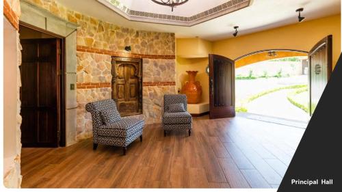 a living room with two chairs and a stone wall at Villa El Retiro Luxury Property in Alajuela City