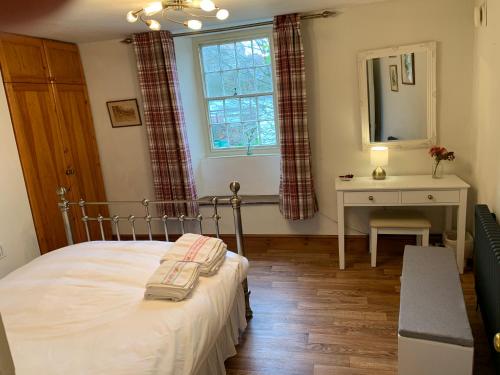 a bedroom with a bed and a desk and a window at Gardener's Cottage in Kingsbridge