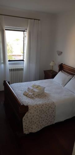 a bedroom with a bed with white sheets and a window at Casa Esquível in Mourão