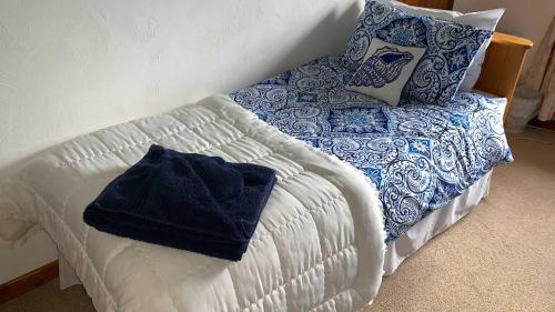 a bed with a blue and white blanket and pillows at The Grannary in Sidmouth