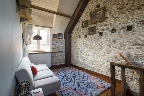 a living room with a couch and a stone wall at Glatigny Farmhouse - close to beach - proche de la plage in Glatigny