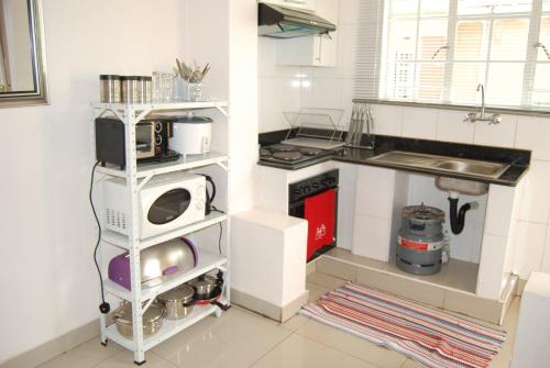 a kitchen with a sink and a microwave on a shelf at Lonjeta Self-Catering Apartments in Lilongwe