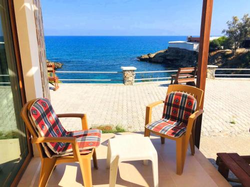 two chairs and a table on a balcony with the ocean at SEA & SKY Bungalows Escape Beach Guest Rooms in Kérynia
