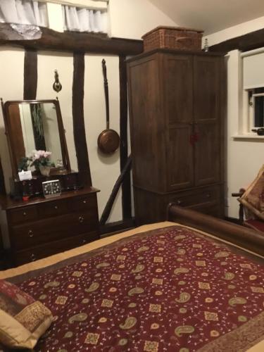 a bedroom with a bed and a dresser and a mirror at Ivy Todd cottage in Debden