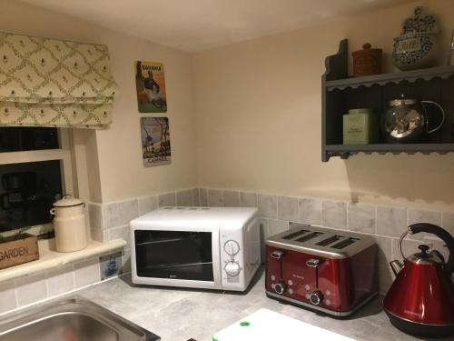a kitchen with a microwave and a toaster oven at Ivy Todd cottage in Debden