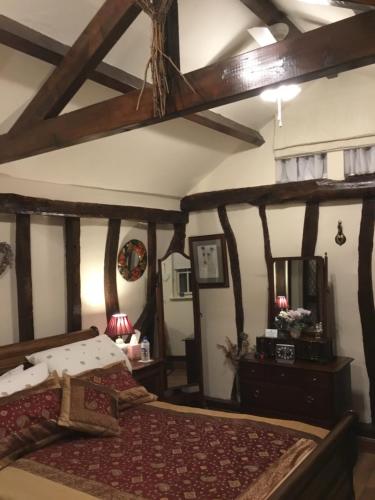 a bedroom with a large bed with wooden beams at Ivy Todd cottage in Debden