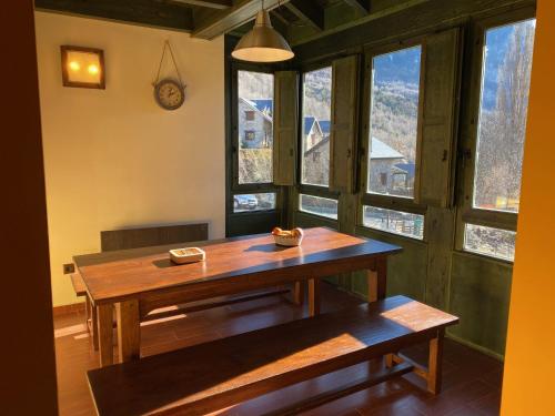 une table et un banc dans une pièce avec fenêtres dans l'établissement Apartamento ático-dúplex en Casa Rural Fundanal en Hoz de Jaca, à Hoz de Jaca