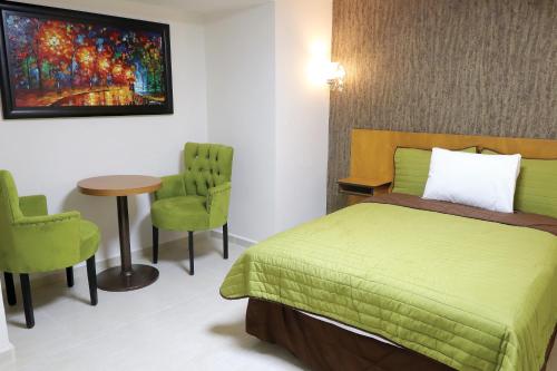 sypialnia z zielonym łóżkiem oraz stołem i krzesłami w obiekcie Royal Madero Inn w mieście Ciudad Madero