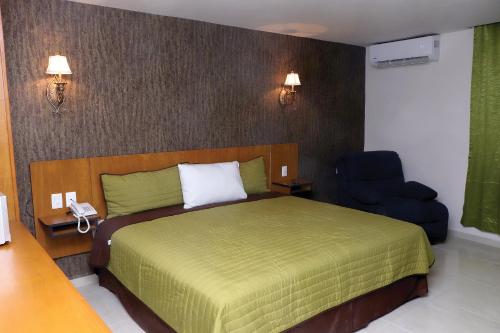 a bedroom with a green bed and a blue chair at Royal Madero Inn in Ciudad Madero