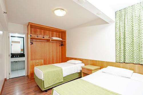 a small room with two beds and a television at Slim São Paulo Congonhas in Sao Paulo