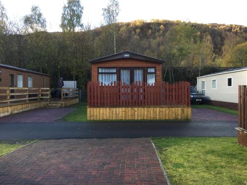 a wooden fence with a gate in a yard at 81 The Heathers, Aviemore Holiday Park , Dalfaber rd Aviemore PH22 1PX in Aviemore