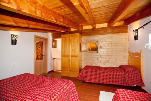 a bedroom with two beds in a room with wooden ceilings at Can Prats in Ríudecañas