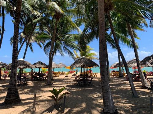 a beach with palm trees and tables and chairs at Summit Pousada Noah in Maceió