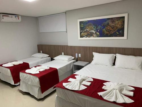 Habitación con 2 camas y mantas rojas y blancas. en Summit Pousada Noah, en Maceió