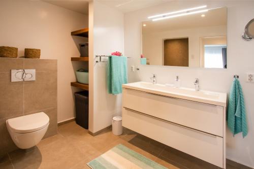 a bathroom with a sink and a toilet and a mirror at Palms & Pools apartment at Curacao Ocean Resort in Willemstad