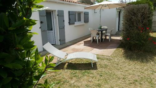 un patio avec une table, des chaises et un parasol dans l'établissement MAISON VENDEENNE PROCHE DE L OCEAN, à Saint-Jean-de-Monts