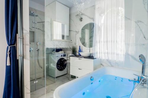 a white bathroom with a tub and a shower at El Dorado Apartment z Jacuzzi in Wrocław