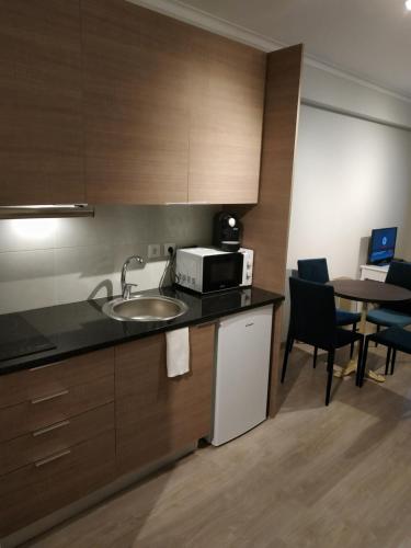 a kitchen with a sink and a microwave and a table at ML Apartments Avenue in Porto