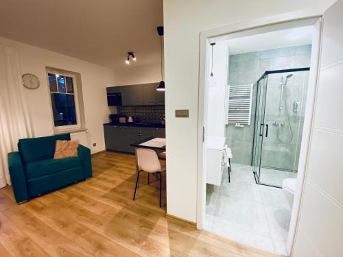 un salon avec un canapé bleu et une salle de bains. dans l'établissement Apartament przy Parku, à Polanica-Zdrój