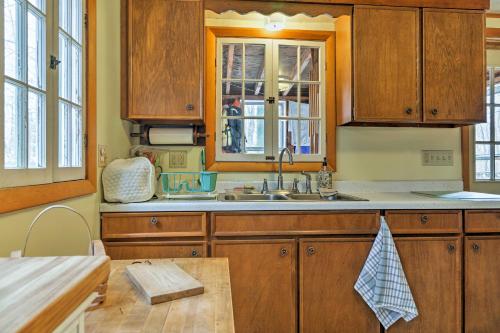 una cucina con armadi in legno e lavandino di East Otis Reservoir Cabin with Porch - Walk to Lake! a East Otis