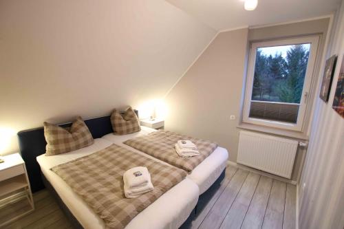 a bedroom with a bed with two towels on it at Haus Eichenhain FeWo Hamburg in Scheeßel