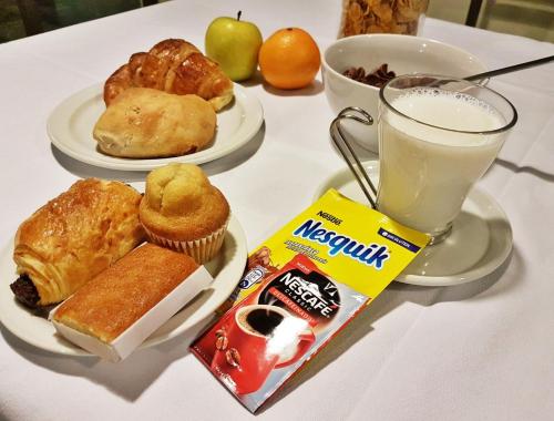 un tavolo con piatti di pasticcini e un bicchiere di latte di Hotel Windsor a Santiago de Compostela