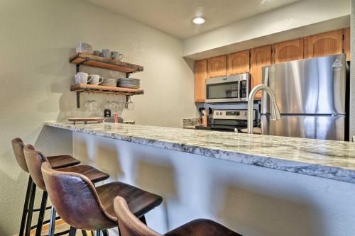 a kitchen with a counter with chairs and a refrigerator at Walk to Main St Frisco Condo with Community Pool! in Frisco