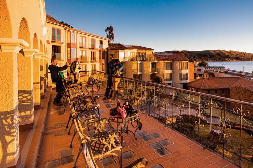 a group of people standing on a balcony with tables and chairs at Hotel Rosario Lago Titicaca in Copacabana