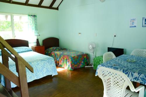 1 dormitorio con 2 camas, mesa y sillas en Gina's Garden Lodges, en Arutanga