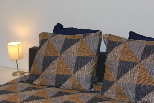 two pillows on a bed next to a lamp at cosy@sea in Middelkerke