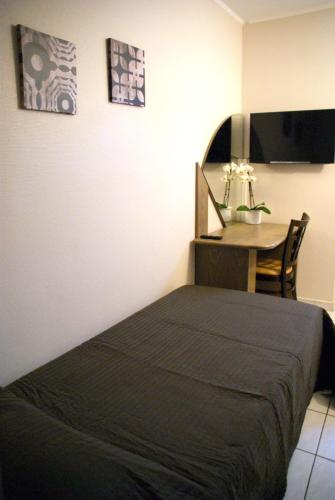 a bedroom with a bed and a table with a television at Charly's Gare in Senningerberg