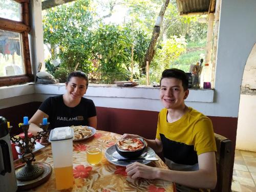 a man and a woman sitting at a table with pizza at Green Hostal Popayan in Popayan