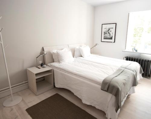 a white bedroom with a large white bed and a lamp at Sands Hotell in Sandhamn