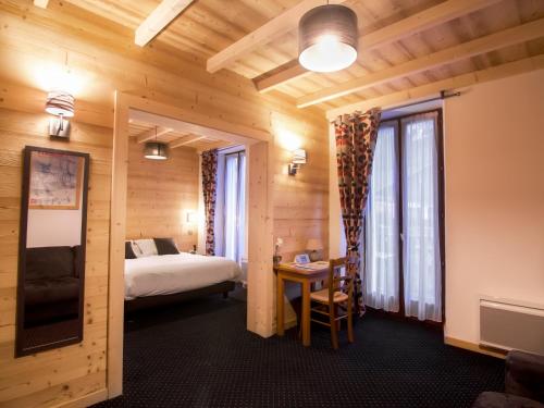 a hotel room with a bed and a desk and a bed at Hôtel Le Bellevue in Thollon